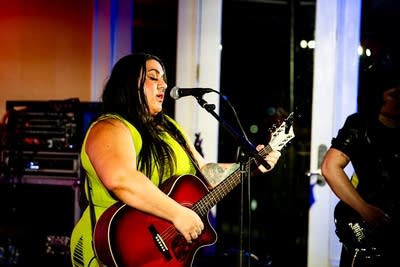 A musician sings and plays guitar onstage