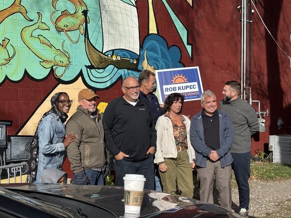A group of politicians poses for a photo in front of a mural.