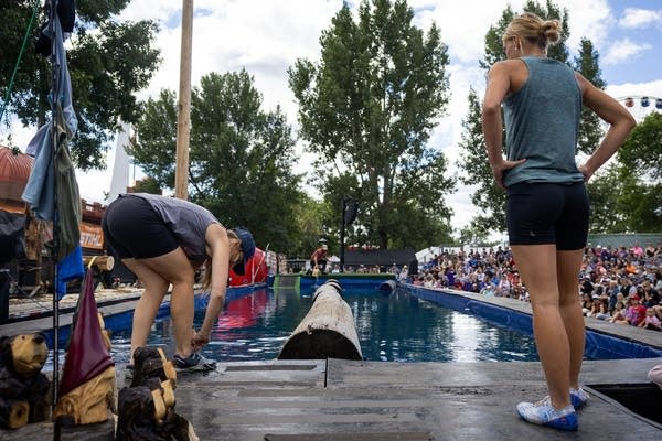 Two women stand next to a pool