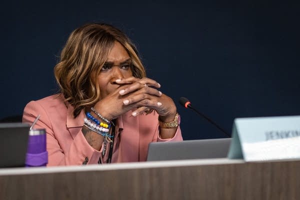 A woman clasps her hands together and listens