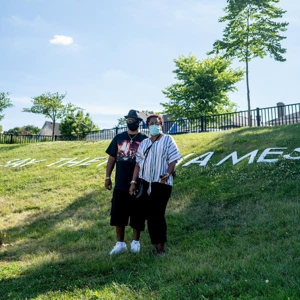 A man and a woman stand on a hill.