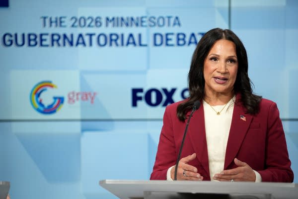 woman in red speaks behind a podium