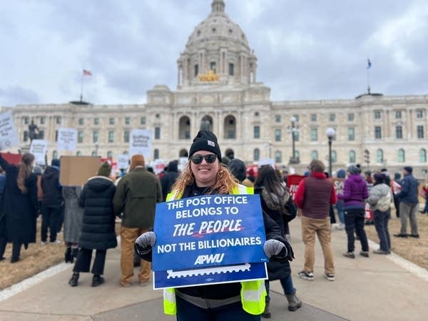 a woman holds a sign outside the minnesota capitol