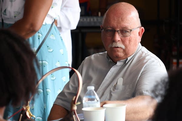 A man sits at a table in a crowded room.
