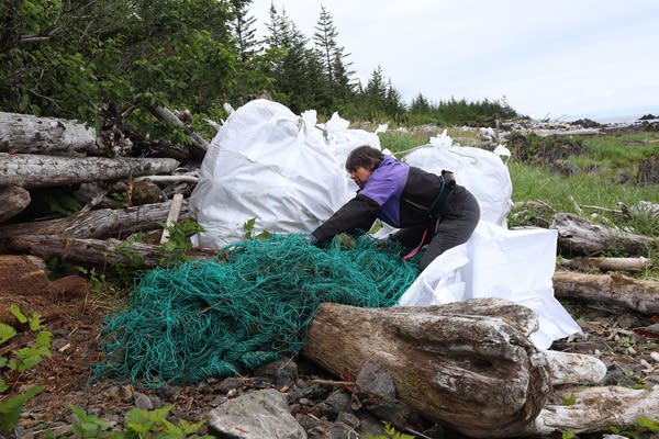 A woman grabs a fishing net on a beach.