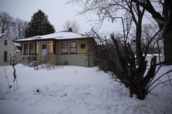 A one-story yellow house on a snowy yard.