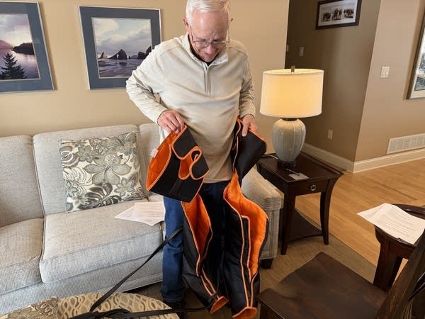 Steve Ronningen shows off a product that has helped him sleep alongside his medication regimen. The heating pad wraps around his legs and provides compression, which offers Ronningen some relief.