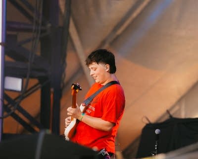 A musician plays guitar on a large outdoor stage