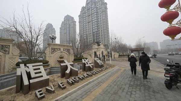 Above, people walk past an Evergrande residential complex called Evergrande Palace in Beijing in January 2024.