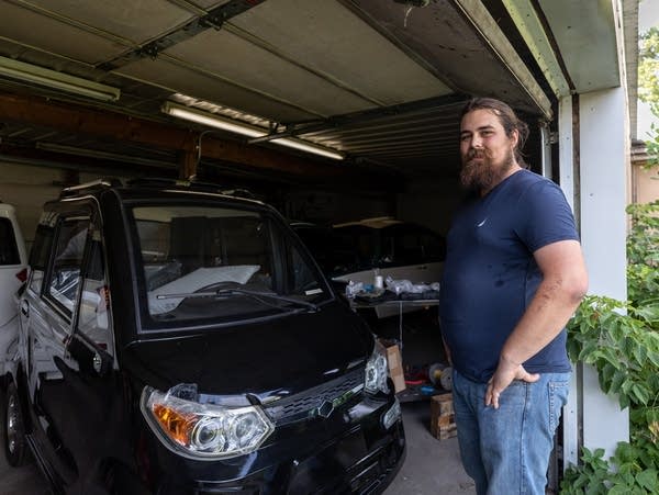 A man stands in the doorway to a garage