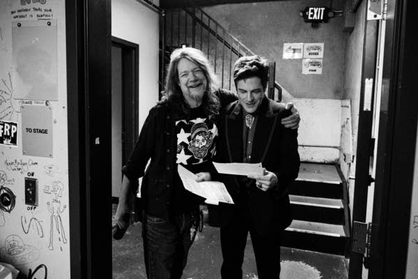 Two musicians pose for a photo backstage before a concert