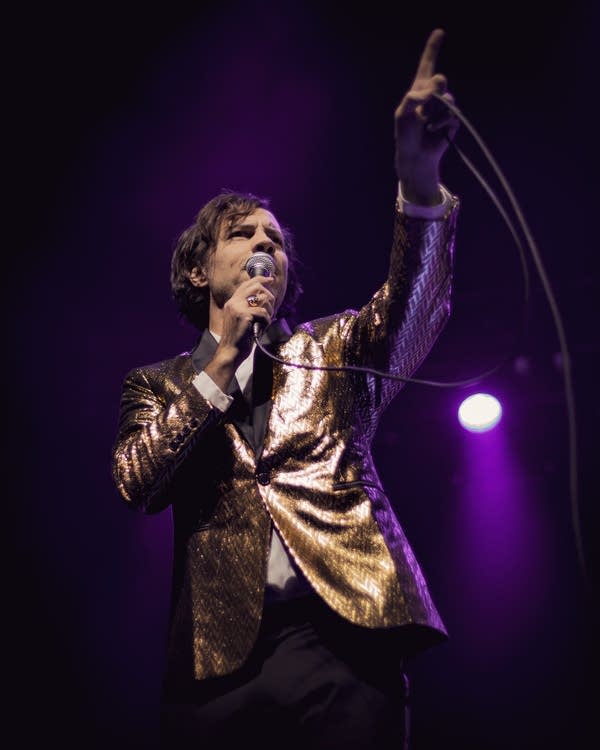 A man in a shiny jacket holds a microphone
