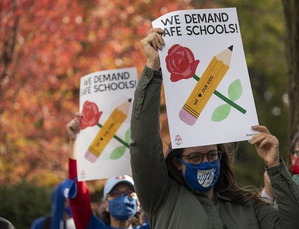 A person holding a sign that reads "We demand safe schools"