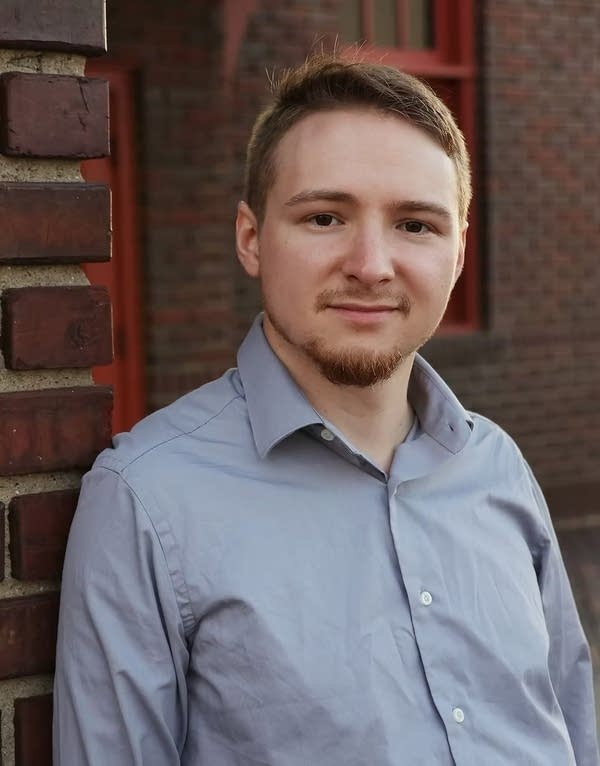 A man stands outside a brick building for a portrait