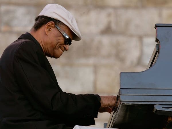 A man sits playing a grand piano.
