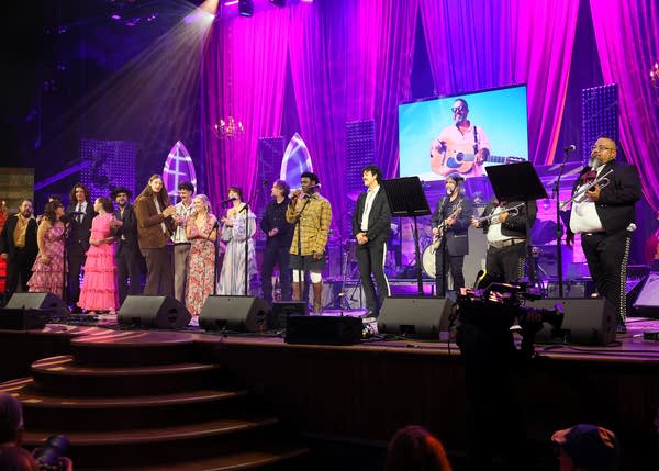 A large group of musicians perform a song together