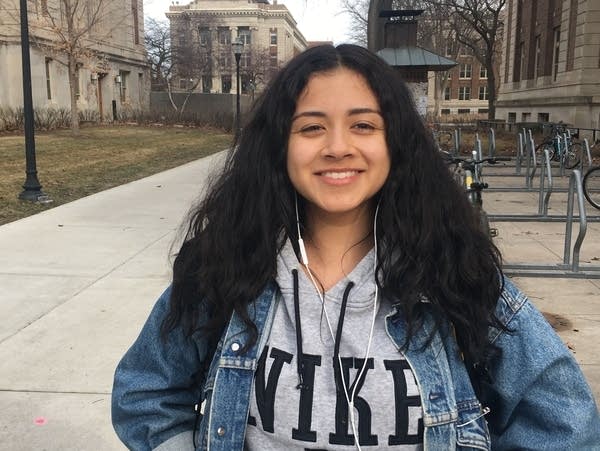 A U of M student stands in front of a school building.