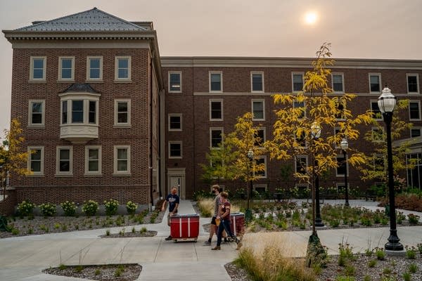 People walk away from a building under hazy skies. 