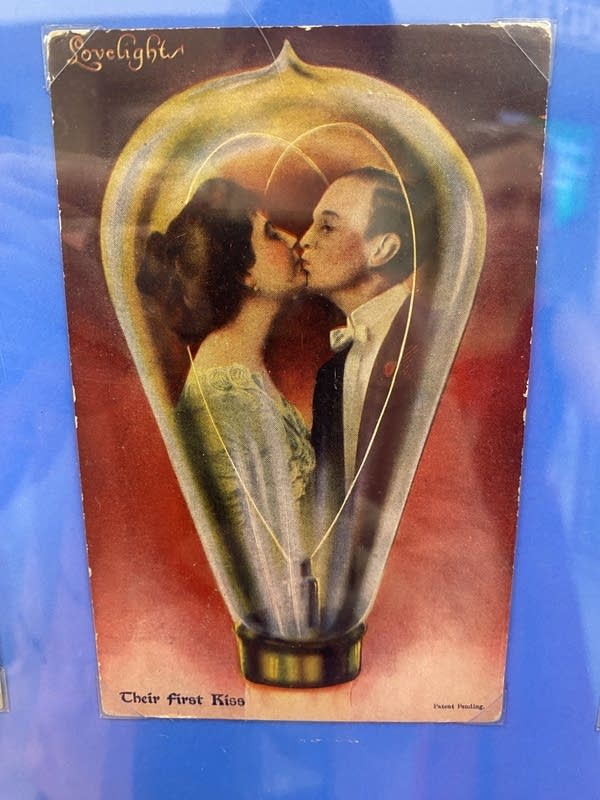 A vintage painting of a man and woman kissing within a lightbulb.
