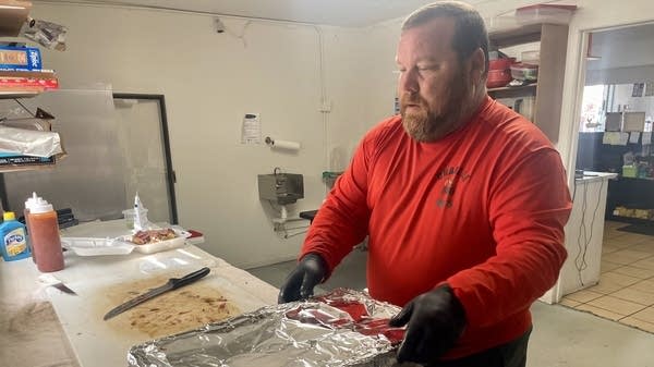 Pitmaster Rusty Rohan cuts through smoked brisket to fill orders at his restaurant Charlie Ro's BBQ in Taylor, Texas. 