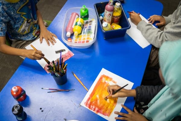 Three children paint at a table
