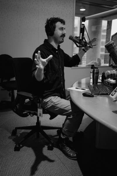 Zach McCormick sits at a table and speaks into a microphone.