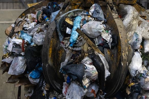 A large claw lifts trash