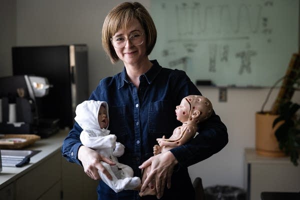 A woman holds two baby dolls used for apparel design