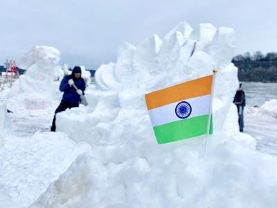 A team carves a lotus flower into a snow sculpture.