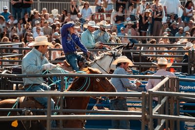 A cowboy spins a lariat while others watch him