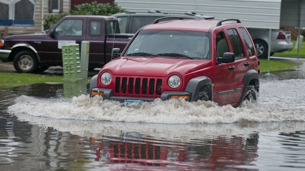 A driver plows through flooded Mankato street.