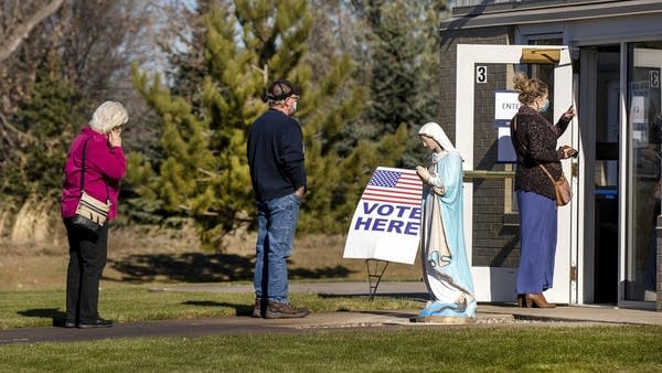 People wait in line outside a church. 