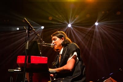 A musician sings and plays keyboards onstage