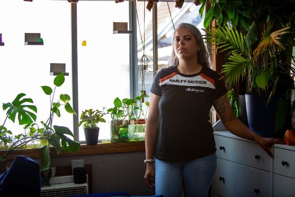 A person stands near potted plants on display around the house.