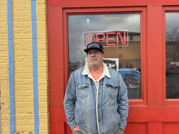 Man posing for photo in front of open sign
