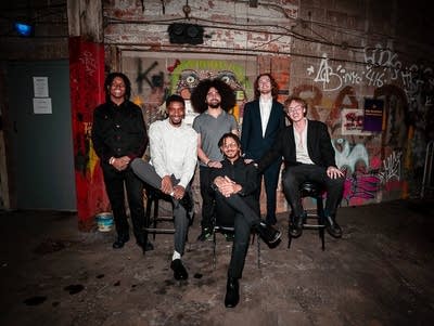 Six musicians pose for a photo in a garage.