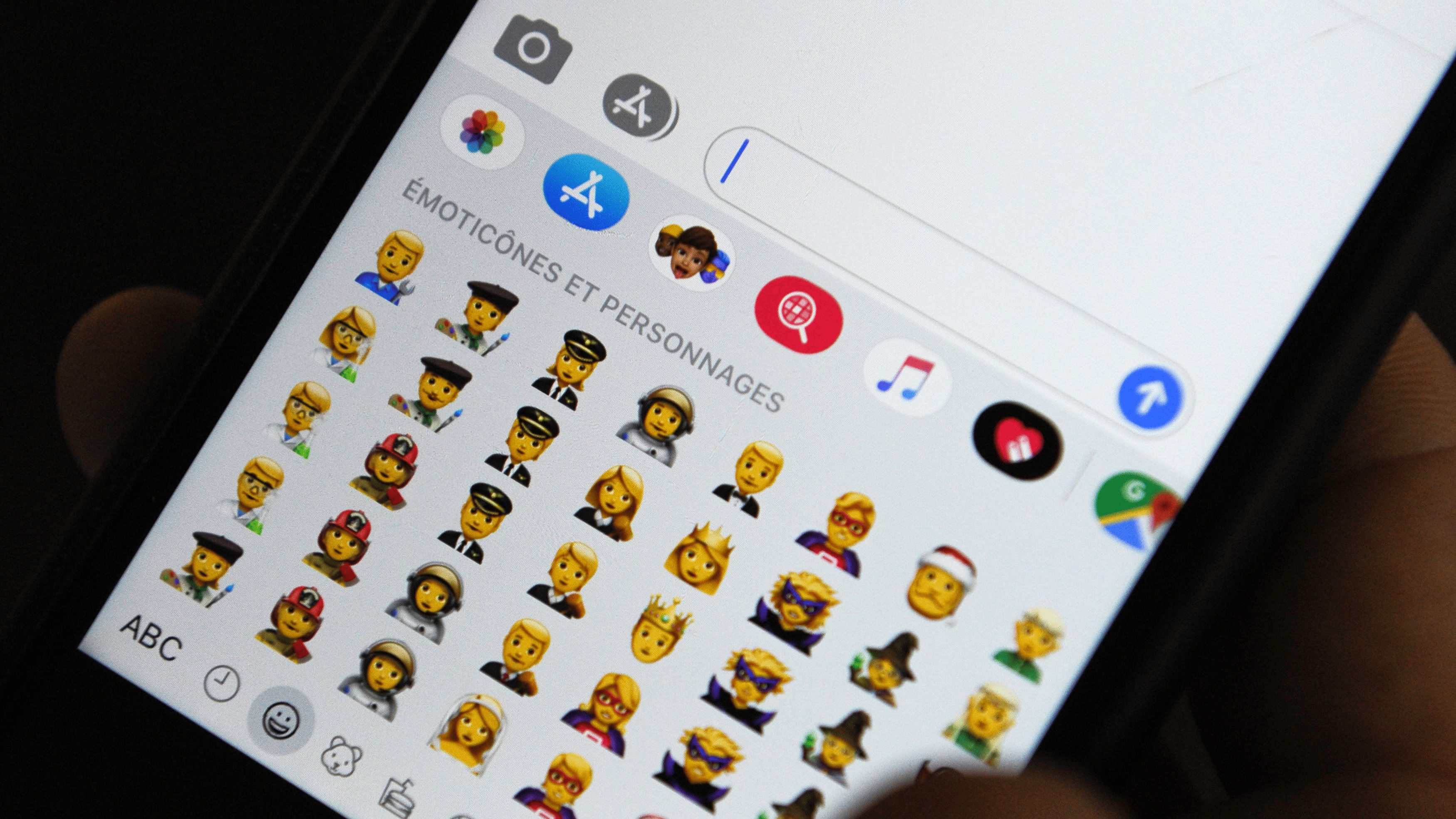An iPhone shows a menu of an array of emojis of different occupations.