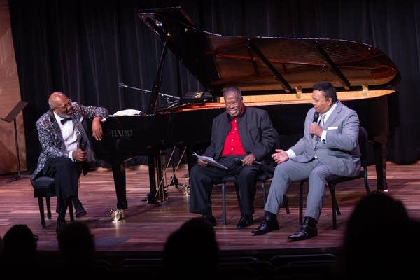 three people sitting on a stage for an interview