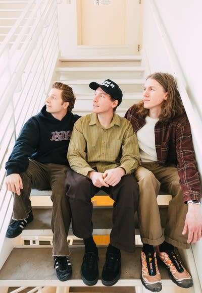 Three guys sit on a staircase together for a portrait