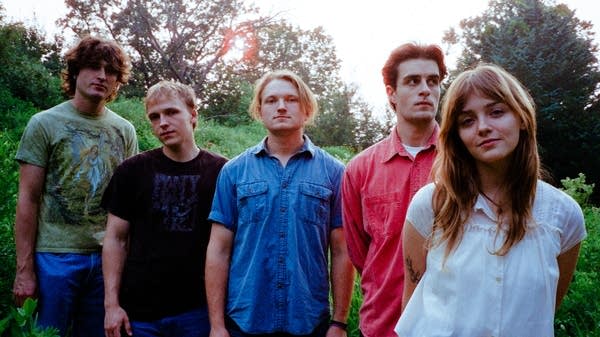 Five people stand in a grassy field.