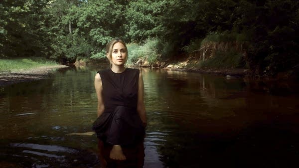 Poster Composer Sarah Kirkland Snider sits in a river