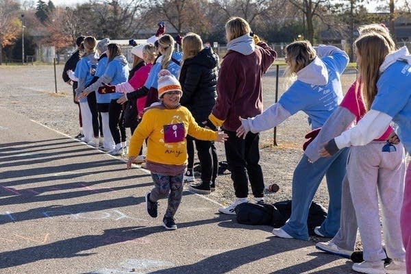 People high five a girl who is running 