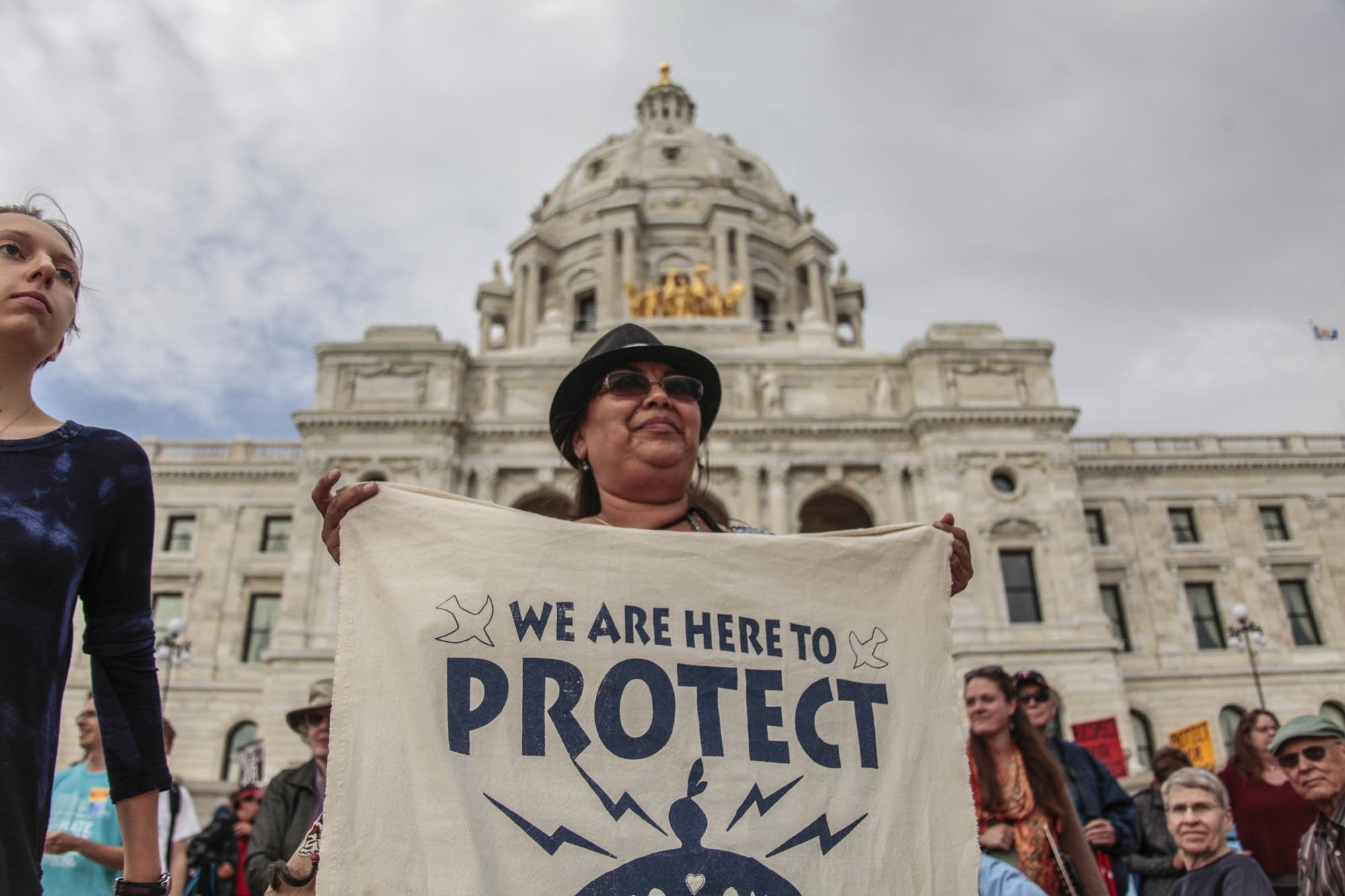 Debra Topping holds a water protect sign in front of the Capitol.