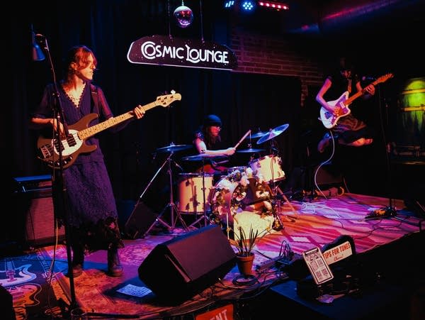 Three members of a band perform on a concert stage.