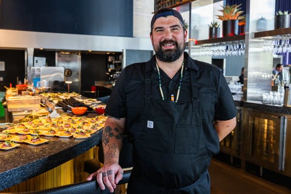 A man stands in a serving area of a restaurant.