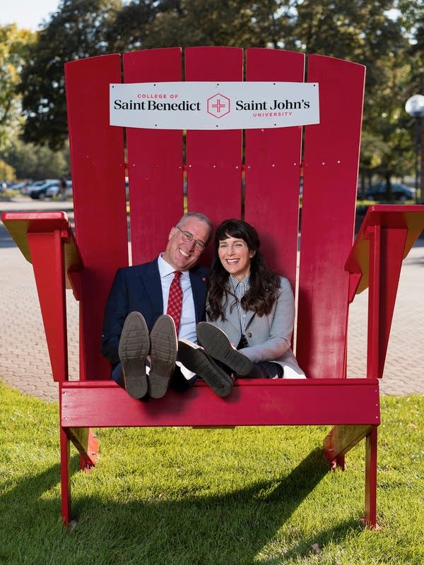 man and woman seated in giant red adirondack chair