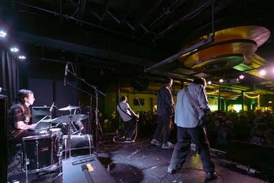 A four-piece band performing onstage in a music venue
