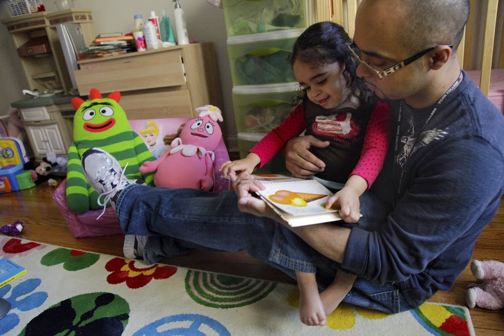 Christopher Astacio reads to his daughter