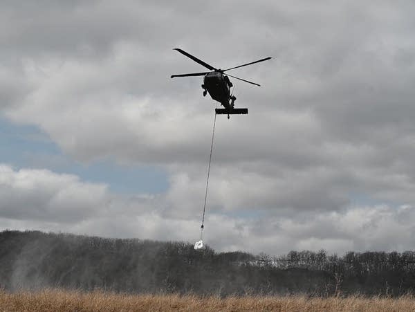 A North Dakota National Guard helicopter lifts a one-ton sandbag