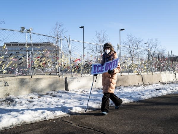 A woman carries a sign reading "ICE OUT!"